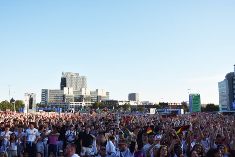 Fanmenge mit Deutschlandflaggen und -trikots auf der Fanmeile am Brandenburger Tor in Berlin.