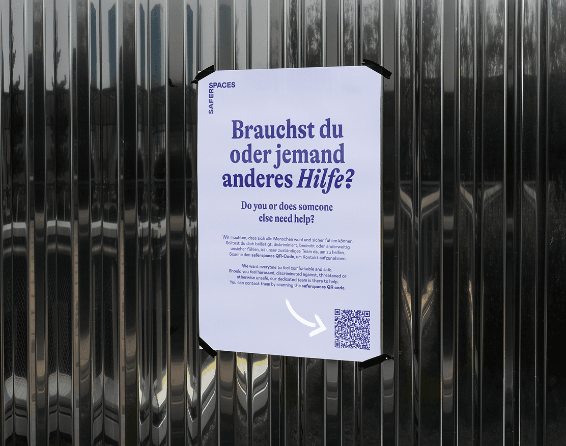 Plakat an Metallwand mit Text: "Brauchst du oder jemand anderes Hilfe?" und QR-Code unten rechts.
