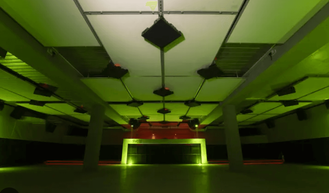 Innenraum des Tokonoma Clubs in grünem Licht mit Bühne und Lautsprechern.