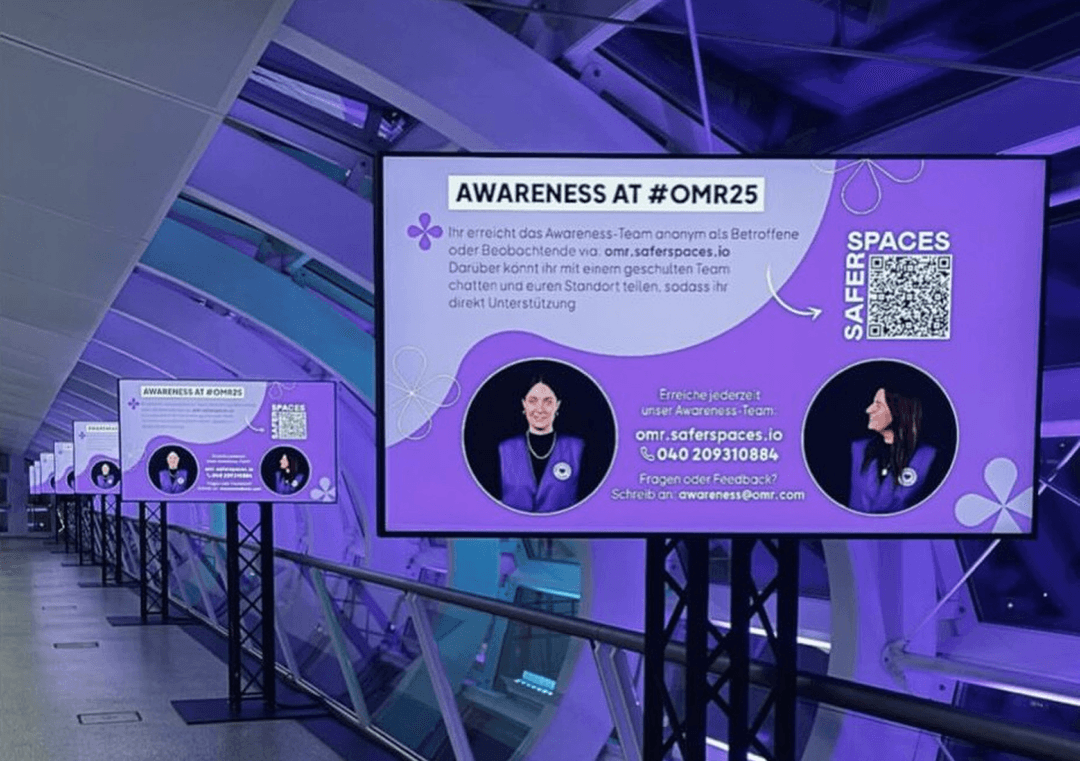 Digital information panels with lavender background inform about safe-guarding at #OMR25 and offer contact possibilities for support.