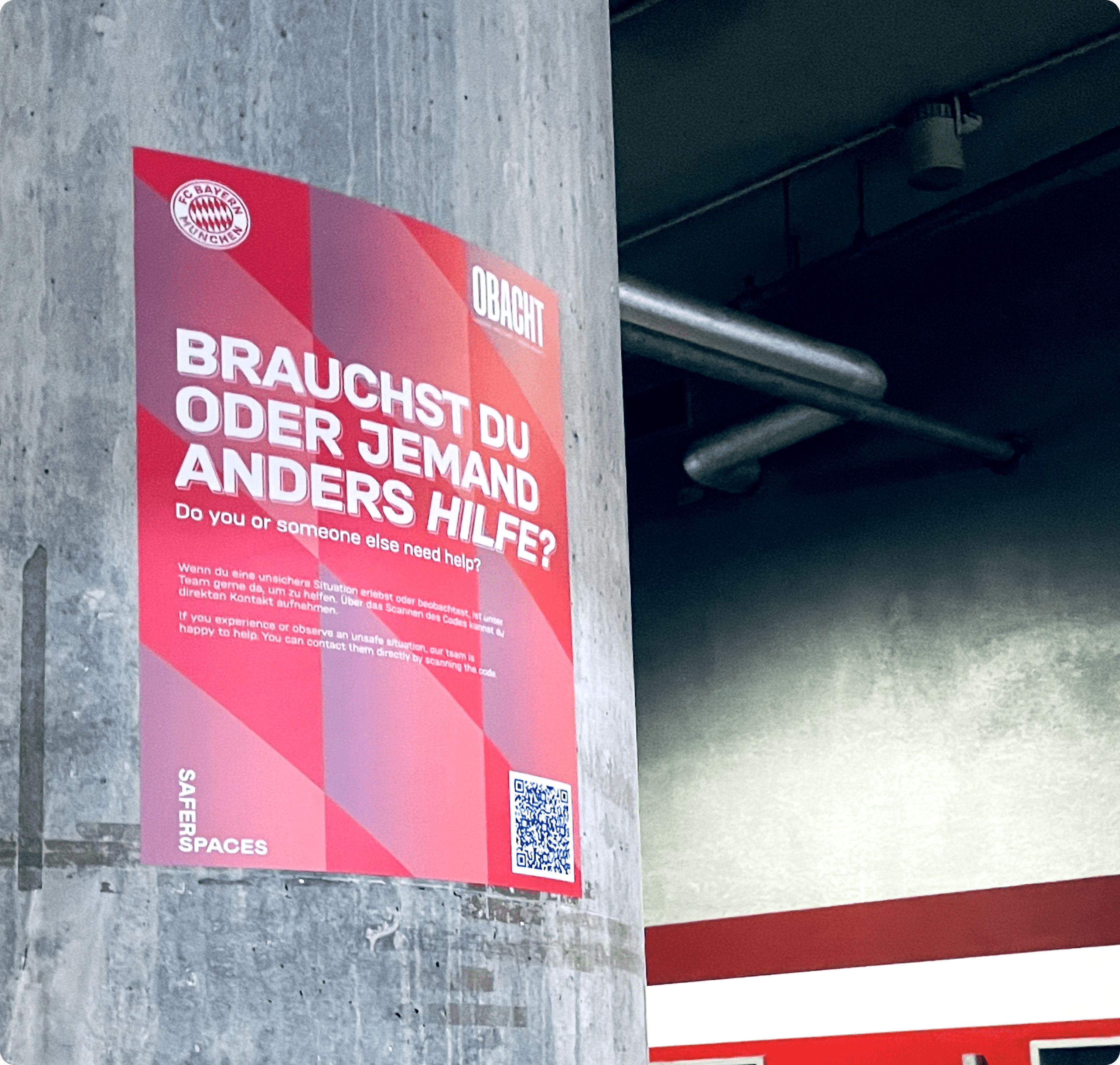 Red poster of FC Bayern Munich on a column with text: 'DO YOU OR DOES SOMEONE ELSE NEED HELP?' and QR code on the bottom right.
