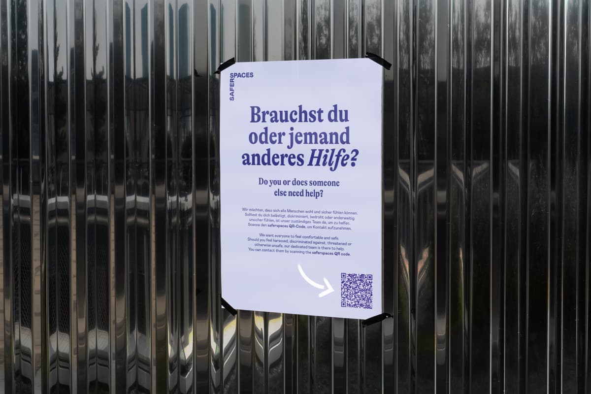 Awareness-Plakat mit QR-Code zur Vorfallmeldung an einem Metallzaun.