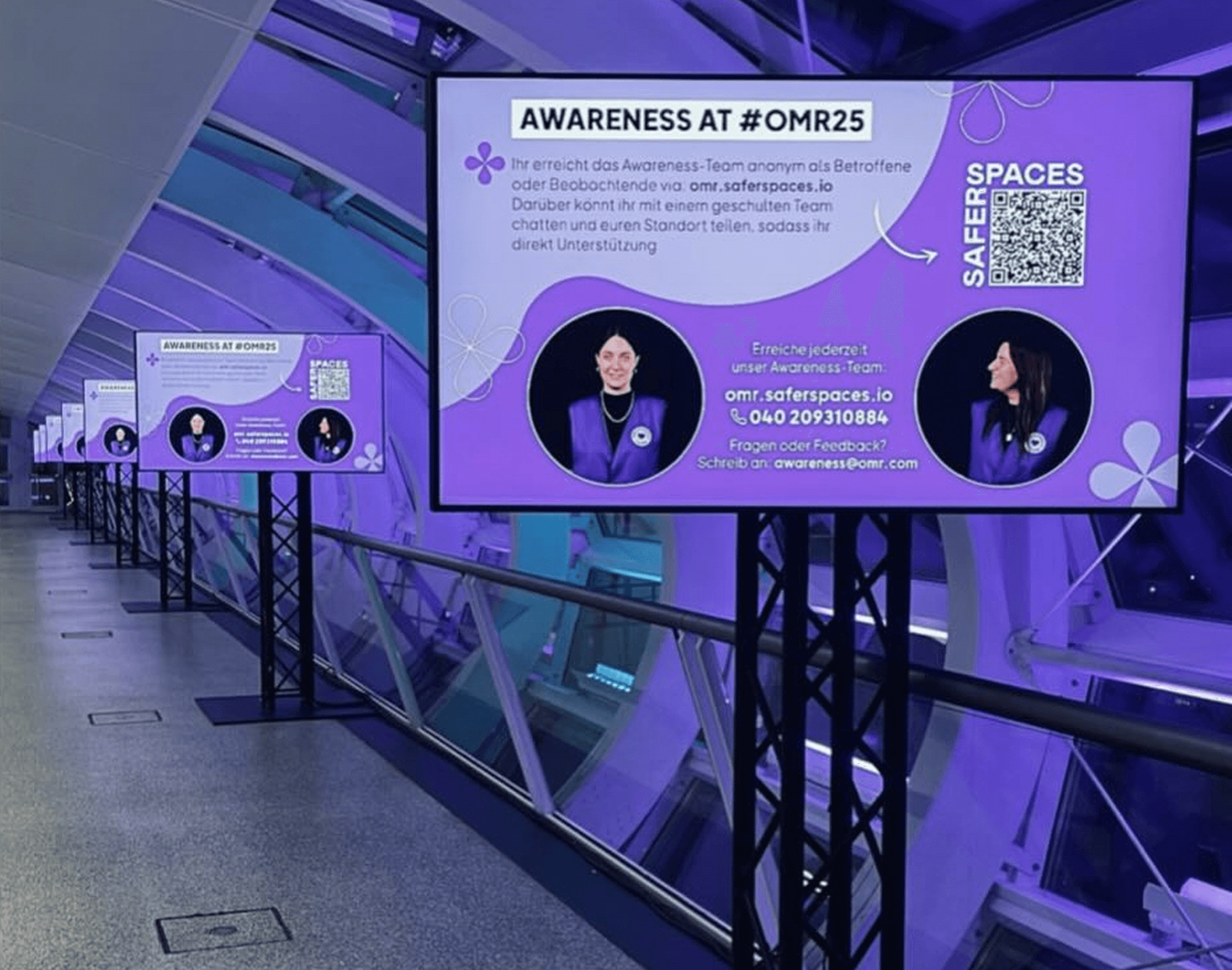 Lavender screens with text „AWARENESS AT #OMR25“, photos of two people and QR code for Safer Spaces.